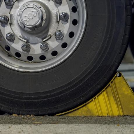 How to Jack Up an RV Trailer Safely: 5 Steps to Keep Yourself Safe 6 wheel chocks are an important thing to know about when learning how to jack up an RV. pictured here are a tire with wheel chock in place to prevent rolling.