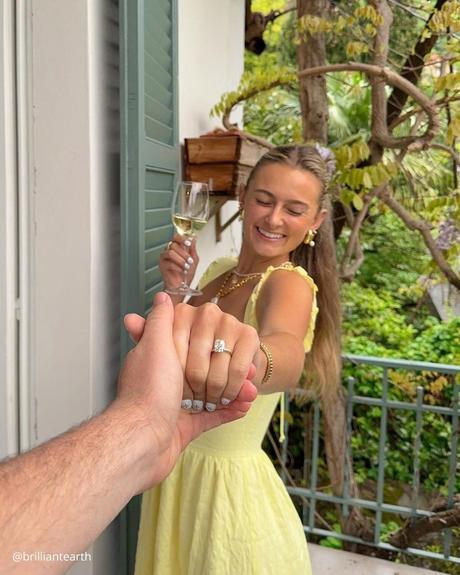 engagement photo captions happy girl with eyes closed and glass of champaign showing her hand with engagement ring after proposal