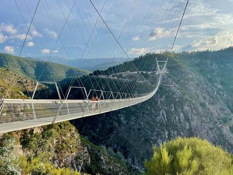 Very long pedestrian suspension bridge across a steep sided valley with people walking across