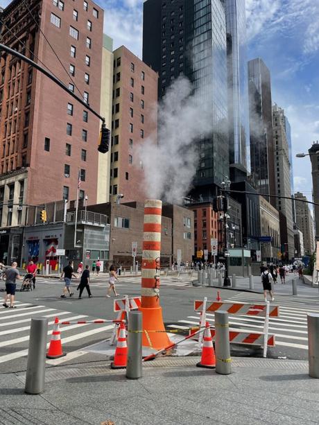 Daytime view of an orange and white steam chimney in downtown NYC