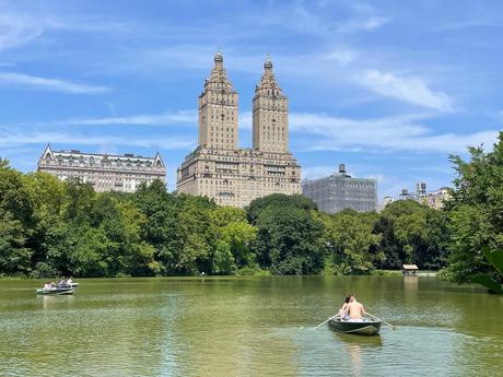 Rowing boat on the lake in central park with old tall buildings beyond