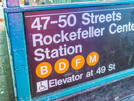 NYC subway sign for 47-50 street Rockefeller Center station with orange circles showing the B, D, F, and M trains