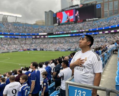 A Real Madrid fan holds his hand across his chest during the national anthem before the game begins.