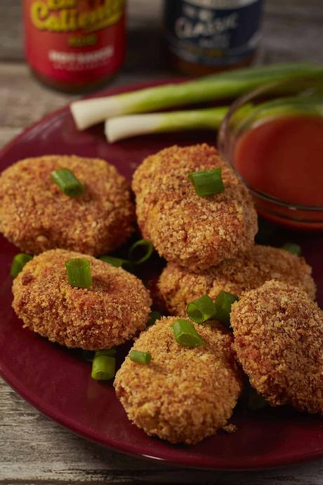 a plate of spicy vegan chickpea nuggets with sauce and green onions