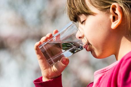 child drinking water out of a glass