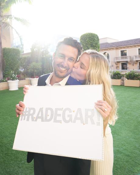 proposal story of tanya rad and roby yadegar couple holding a sign after engagement