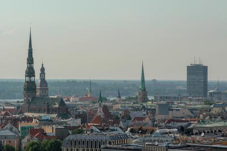 A close-up view of Riga’s historic skyline, featuring several prominent church spires and towers, including St. Peter’s Church, against a hazy backdrop.