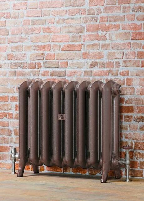 copper cast iron radiator on a brick wall to match the colour of the year 2025