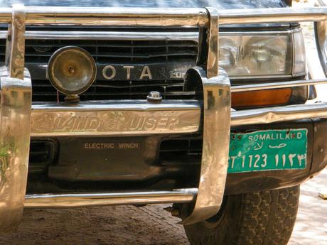 The chrome front of a Toyota Land Cruiser with a green Somaliland license plate and a mounted spotlight on the bumper.