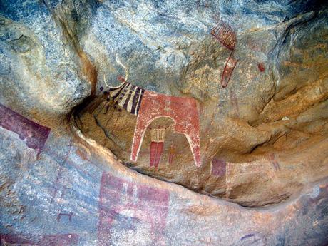 Rock art depicting a stylized animal figure with intricate patterns, painted in red and black, on the wall of a cave in Somaliland.