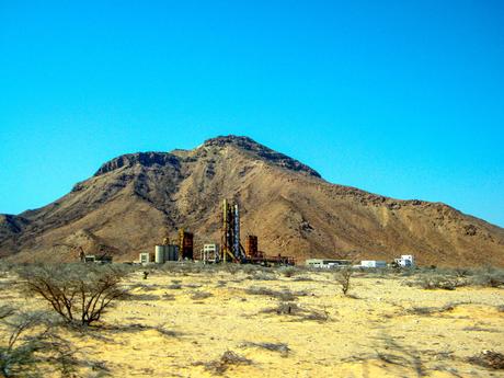 Industrial structures, including tall towers and storage tanks, set against a barren mountainous landscape in Somaliland.