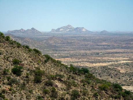 Expansive view of a dry, rugged landscape in Somaliland, with distant mountain ranges under a clear blue sky.