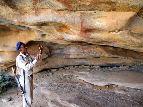 A security guard and local guide wearing a uniform points out ancient rock art paintings on the ceiling of the Laas Geel caves in Somaliland.