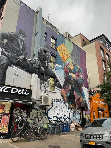 A mural featuring Run-D.M.C., with graffiti and street art surrounding a NYC deli in Manhattan.