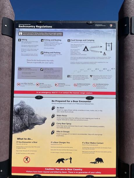 A large informational sign about backcountry regulations in Yellowstone, including tips on encountering bears, food storage, and safety precautions for hiking.