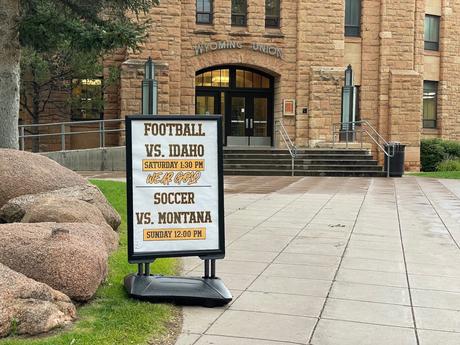 A sign on the University of Wyoming campus promoting football and soccer games, placed in front of the Wyoming Union building.