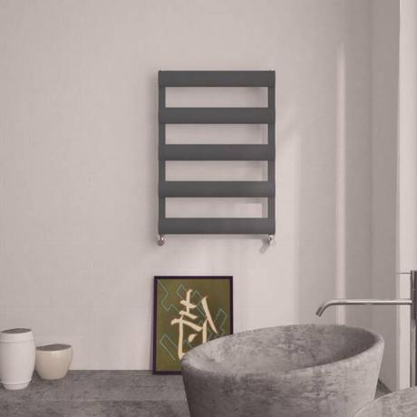 An aluminum heated towel rail on a wall above a sink in a bathroom