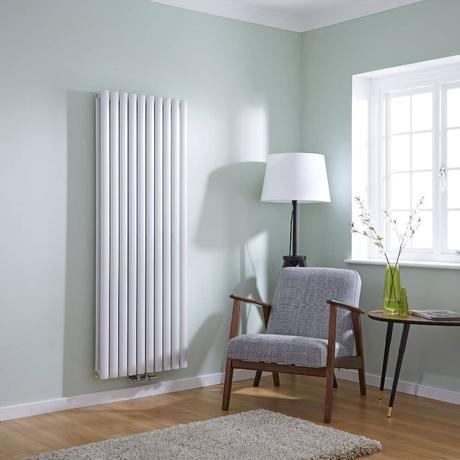 Modern white vertical radiator on green wall