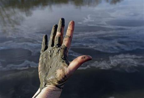 Amy Adams, North Carolina campaign coordinator with Appalachian Voices, shows her hand covered with wet coal ash from the Dan River swirling in the background as state and federal environmental officials continued their investigations of a spill of coal ash into the river in Danville, Va., Wednesday, Feb. 5, 2014. Duke Energy estimates that up to 82,000 tons of ash has been released from a break in a 48-inch storm water pipe at the Dan River Power Plant in Eden N.C. on Sunday.  Photo: Gerry Broome / AP