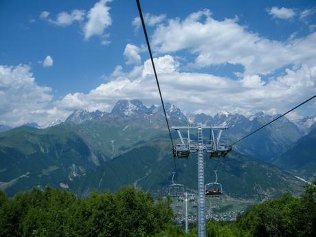 The view from a chairlift, suspended in midair, offers an unparalleled perspective of the towering mountain range, with sharp peaks cutting into the horizon.