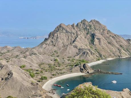 A close-up of a cliff edge at Padar Island with an expansive view of the turquoise ocean and small islets in the distance.