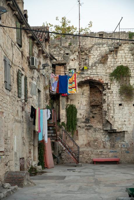 An old stone building with rustic charm, colorful towels and clothes hanging from a line, adding life to the otherwise weathered and aged exterior.