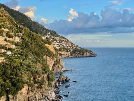 Another view of the Amalfi Coast with calm seas, steep cliffs, and a partly cloudy sky.