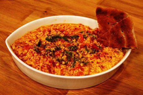 A bowl of traditional Turkish muhammara dip made with roasted red peppers, walnuts, and spices, served with bread.