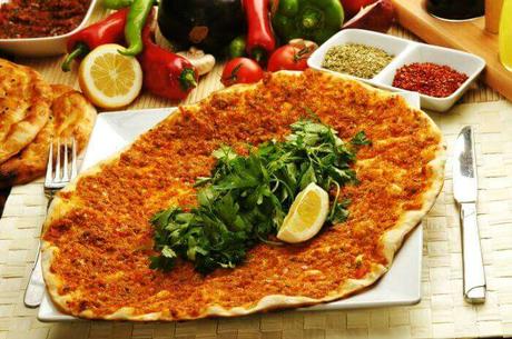 Traditional Turkish Lahmacun topped with minced meat, herbs, and served with fresh parsley and lemon.