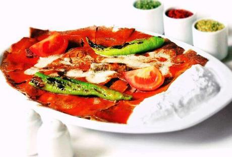 A plate of Turkish Iskender Kebab served with grilled peppers, tomatoes, yogurt, and rich tomato sauce