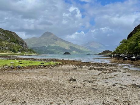 A sheltered bay near Inverie in Knoydart with a deserted beach and mountains rising in the distance across the water.