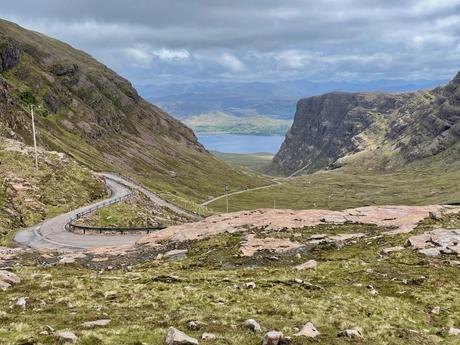 View from near the top of the Bealach na Bà mountain pass with a road winding its way up the pass between sheer cliffs in the mountains of the Applecross peninsula.