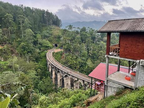 Nine Arches Bridge in Ella, Sri Lanka, viewed from above, with lush green forest surrounding the railway track.