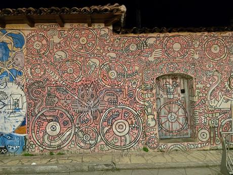 A wall covered in a vibrant, intricate mural featuring symbols, wheels, and abstract shapes in red, white, and black tones.