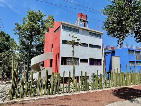 The colorful house of Diego Rivera and Frida Kahlo in San Ángel, Mexico City, featuring bold red and blue walls and a tall cactus fence in front.