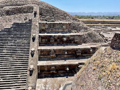 A wider view of the Temple of the Feathered Serpent at Teotihuacan, showing more of the intricate stone carvings and multiple serpent heads along the tiers of the pyramid.