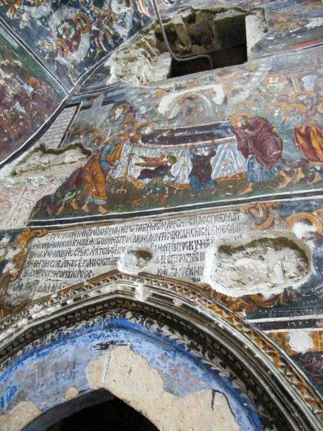 Detailed frescoes depicting religious scenes and Greek inscriptions on the interior walls of the Sumela Monastery.