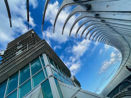 A creative angle of Taipei 101's exterior, featuring a curved metallic design leading the viewer's eye towards a glass facade and blue skies.