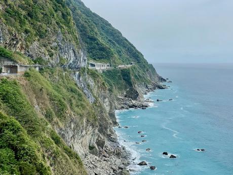 A long stretch of coastal cliffs with tunnels built into the rock, overlooking the vivid blue ocean waves below.