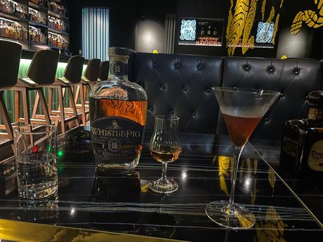 Cocktails and a bottle of rye whiskey on top of a table at a booth inside Just Exchange cocktail bar in Taipei.