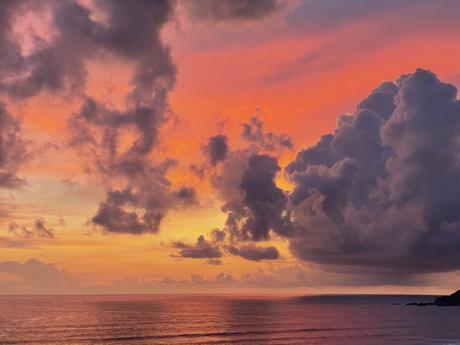 Close-up view of another stunning sunset with hues of orange, pink, and purple blending together in the sky, large clouds catching the last light of the day.