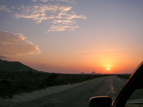 A scenic sunset over a mountainous landscape in Somaliland, with the sun low on the horizon casting a warm glow.