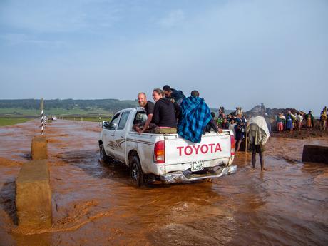 White pickup truck carrying passengers in the back crossing a flooded road in Ethiopia