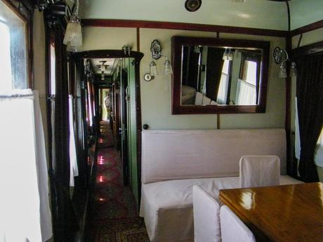 The interior of Joseph Stalin’s personal train carriage in Gori, Georgia, featuring narrow hallways, polished wood paneling, a mirror on the wall, and plush white seating next to a small wooden table.