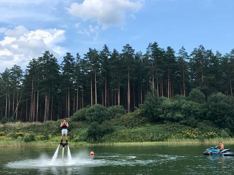 20 Best Places to Visit in Latvia man flyboarding using a water powered hover board and a jet ski on a scenic lake in latvia with pine forests behind