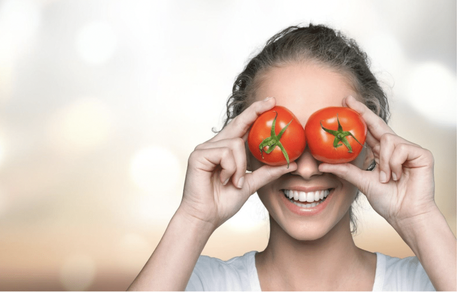 Girl laughing and holding two tomatoes