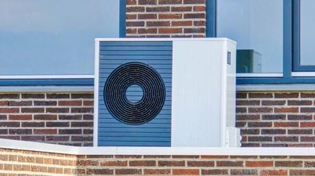 Air source heat pump HVAC unit installed outside a modern house with red brick wall