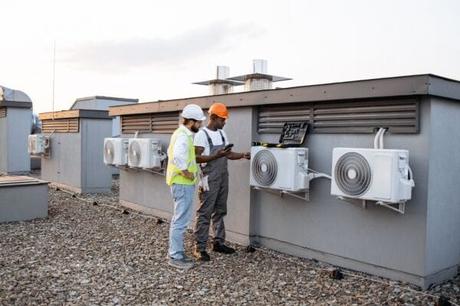 Two construction workers on building roof inspecting HVAC system