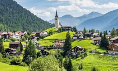 Our 4 Favorite Europe Destination Pairings Graubuenden, Switzerland with view of houses on green grassy hills
