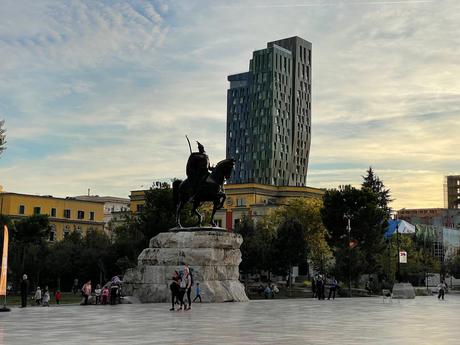 14 Best Things To Do In Tirana (& Surrounding Area) The Skanderbeg Monument in Tirana, Albania, a striking equestrian statue of the national hero, standing tall in the city’s central square. A modern glass tower and historic buildings provide a striking contrast in the background.